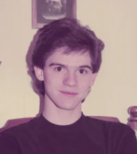 a young man in a black shirt sitting in a chair